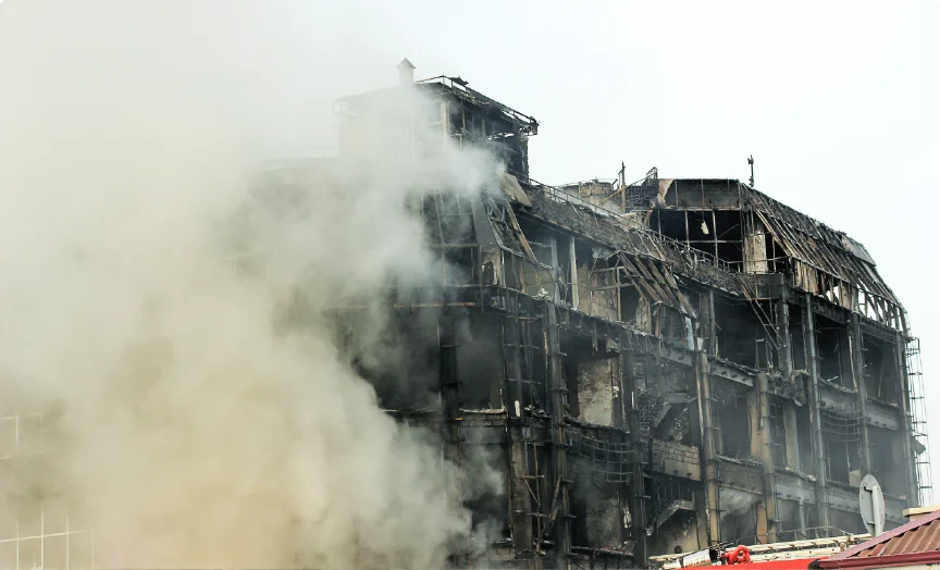 A smoke filled view of a damaged, burned out building.