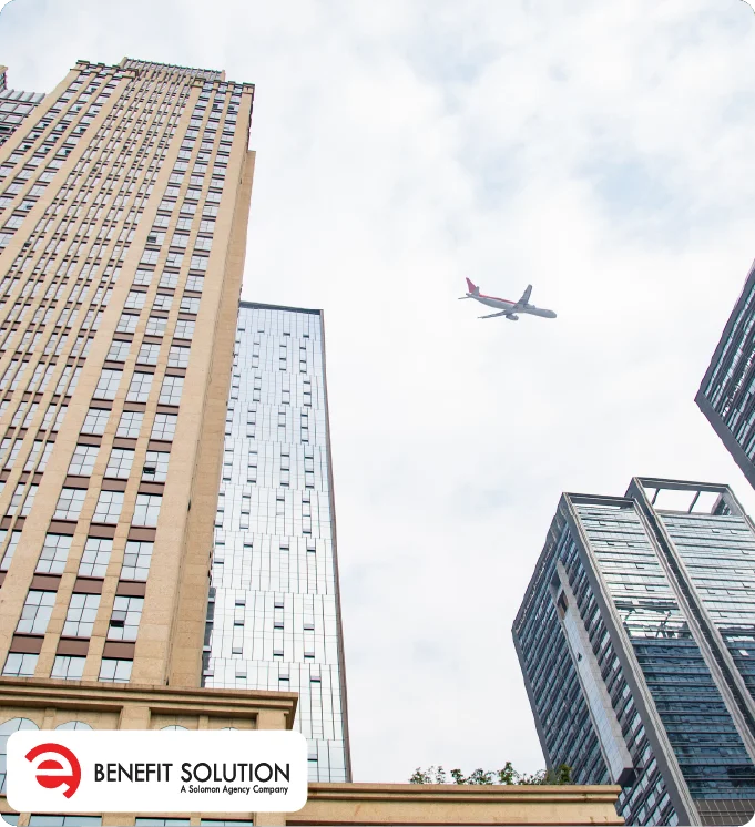 Looking up at tall city buildings with a plane flying overhead and a Benefit Solution logo.