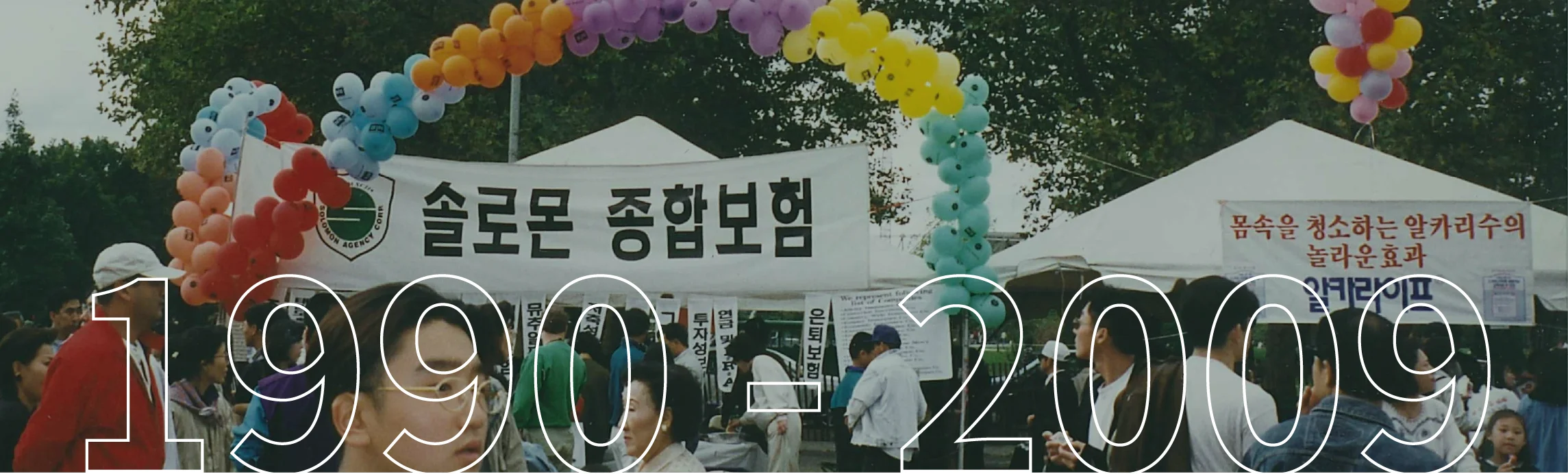 An outdoor community event with a Solomon Insurance banner and the text "1990 - 2009" overlaid.