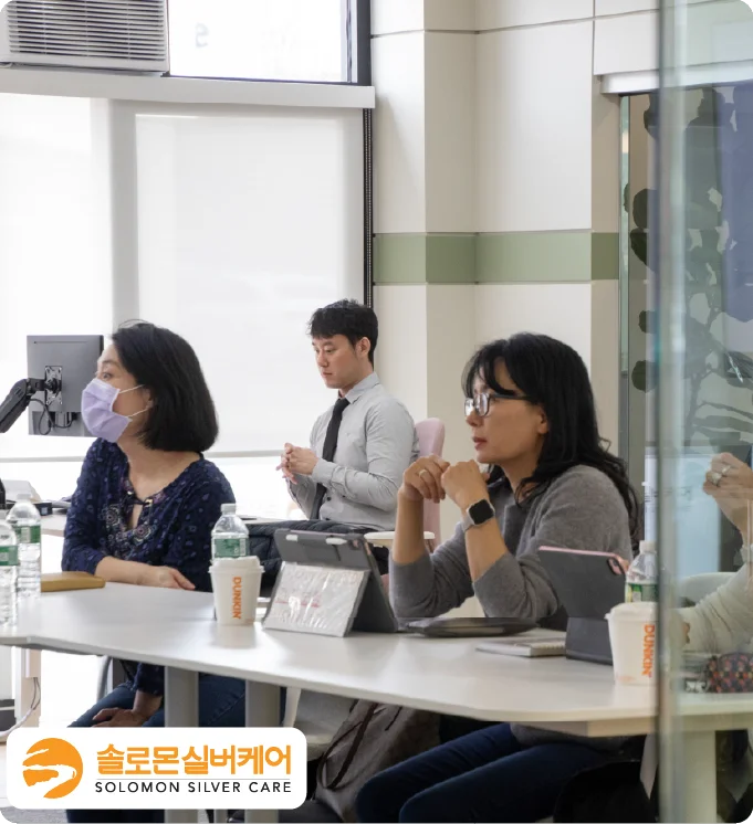 Medicare agents taking a training in a bright meeting room with the Solomon Silver Care logo.