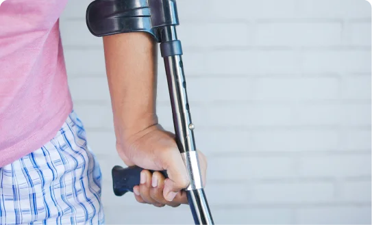 A close-up of a person's hand holding a crutch while walking.