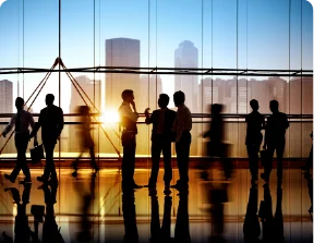 Silhouettes of business people walking and talking in a modern office with a city view.