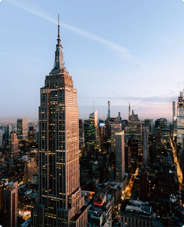 A high-angle view of the Empire State Building and the New York City skyline at dusk.