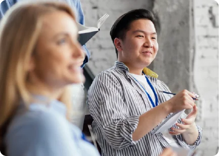 A man and a woman looking forward with bright expressions, representing employee benefits that attract and retain top talent.