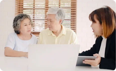 An elderly couple talking with a consultant looking at a laptop screen.