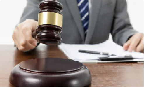 A lawyer in a suit holding a wooden judge's gavel at a desk with official legal documents.