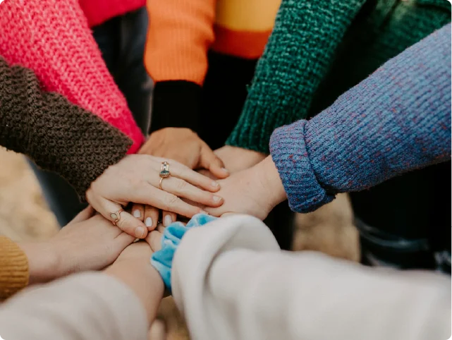 A close-up shot of a diverse group of people stacking their hands together in unity.